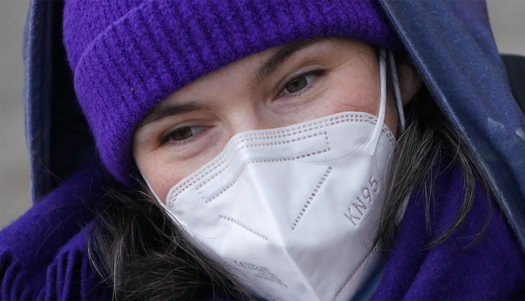 visage féminin avec un bonnet violet et un masque FFP2